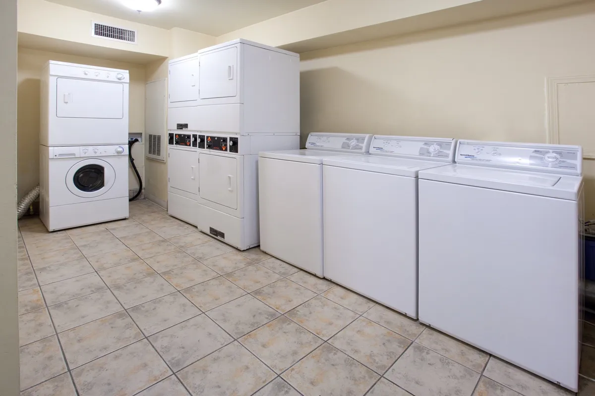 A practical view of the laundry area with washing machines, dryers, and tile flooring. The setup is clean, efficient, and user-friendly, reflecting the convenience of self-serve laundry facilities within the building.
