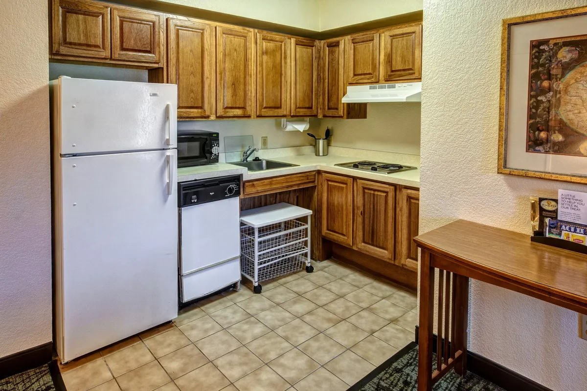 This image presents a welcoming kitchen area, with a refrigerator, modern kitchen cabinets, a sleek sink, stove, and a spacious countertop. The layout suggests ample space for meal prep and social gatherings, highlighting the kitchen's integration with the broader living area. The inviting setup is ideal for both everyday living and communal activities.